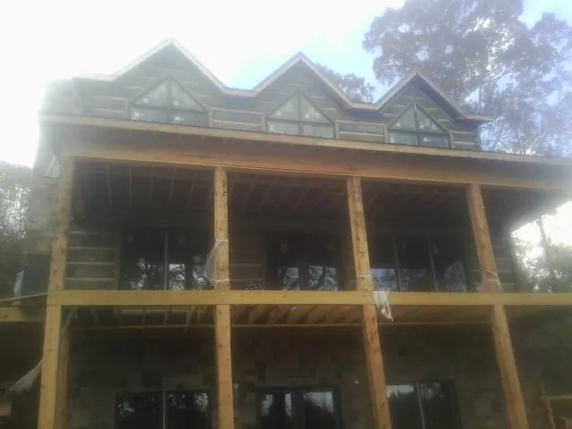 Dormers and porch framing on a large log home under construction — Roof Coating work by our crew in Junction City
