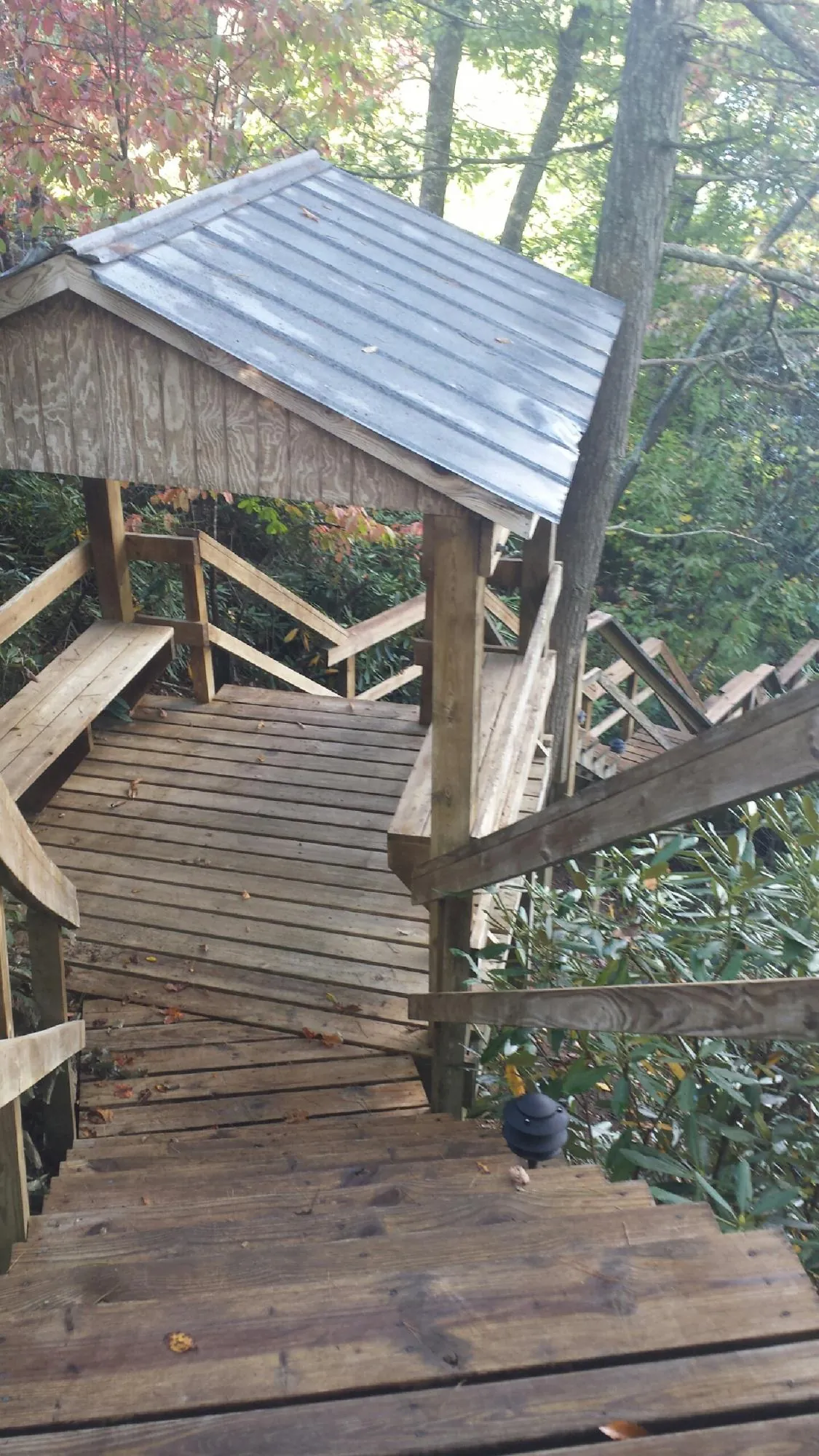 Metal roofed shelter over wooden steps on a wooded walkway — Skylight Repair & Installation work by our crew in Junction City